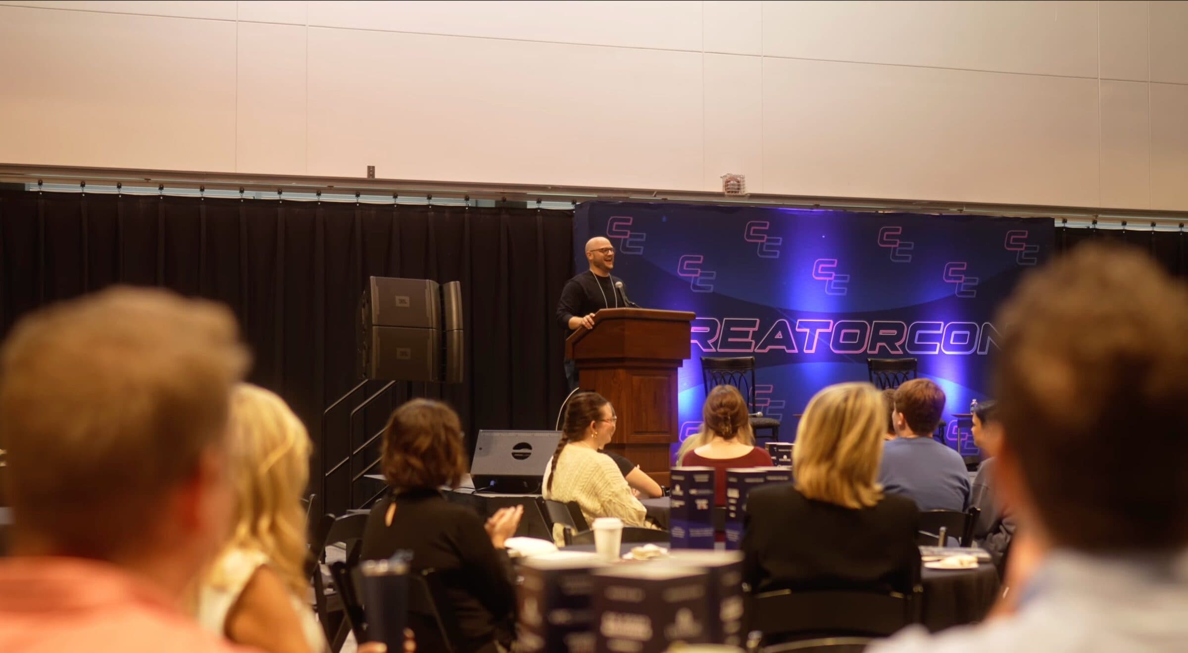 An audience in conversation at a Do Good Foundation event, with the CreatorCon backdrop behind the stage.